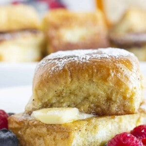 Hawaiian Roll French Toast with butter, syrup, fresh fruit and a sprinkle of powdered sugar.