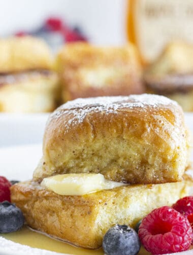 Hawaiian Roll French Toast with butter, syrup, fresh fruit and a sprinkle of powdered sugar.