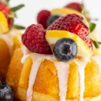 Mini lemon bundt cakes on a red cake plate with fresh fruit.