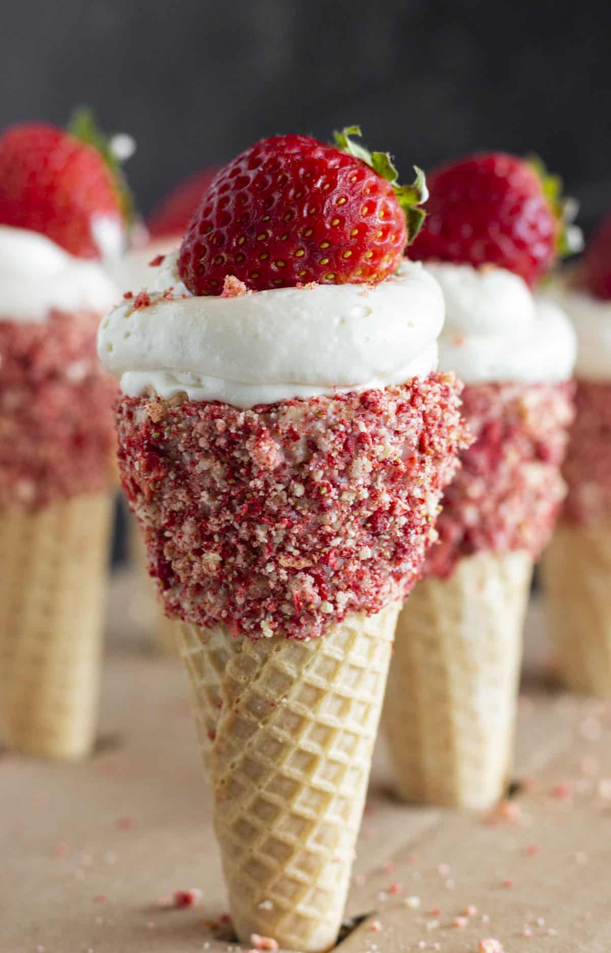 6 Strawberry Crunch Cheesecake Cones with fresh strawberries on top.