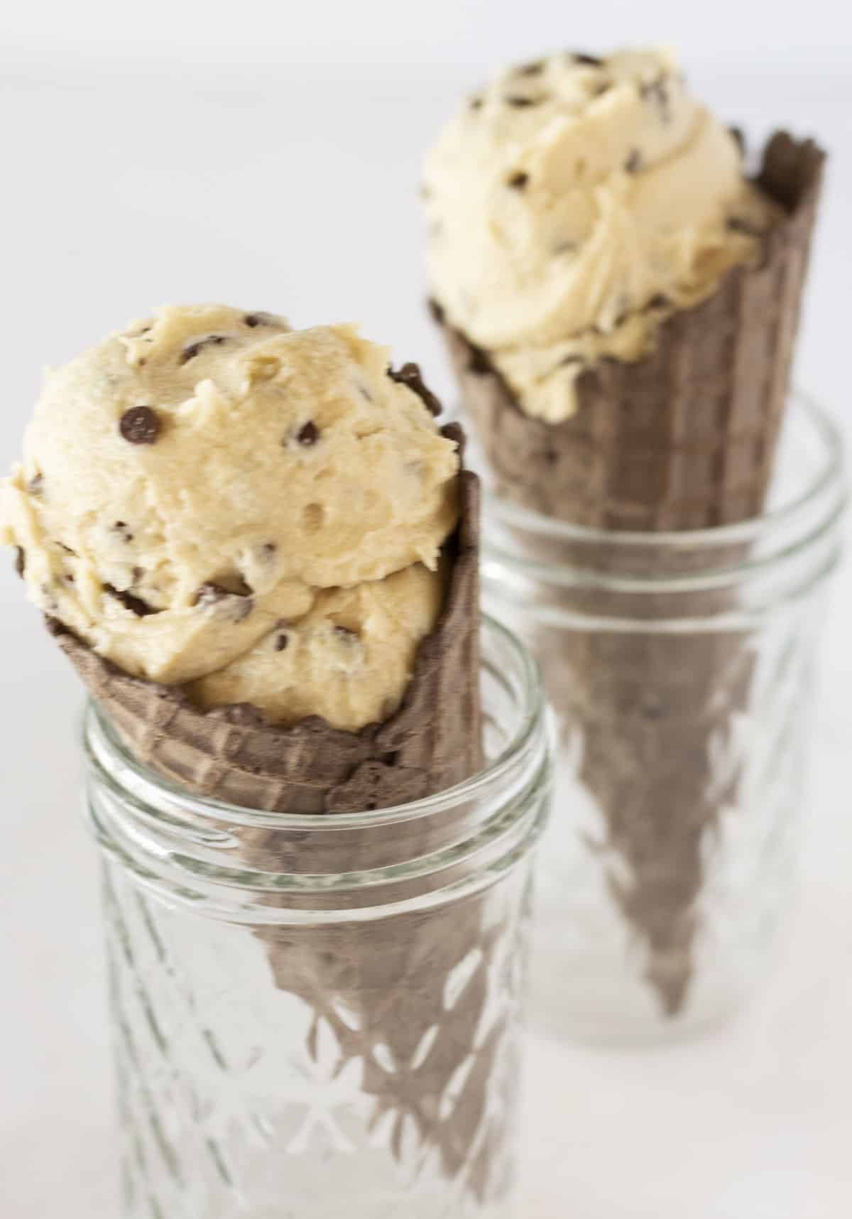 Two chocolate ice cream cones filled with scoops of edible cookie dough.