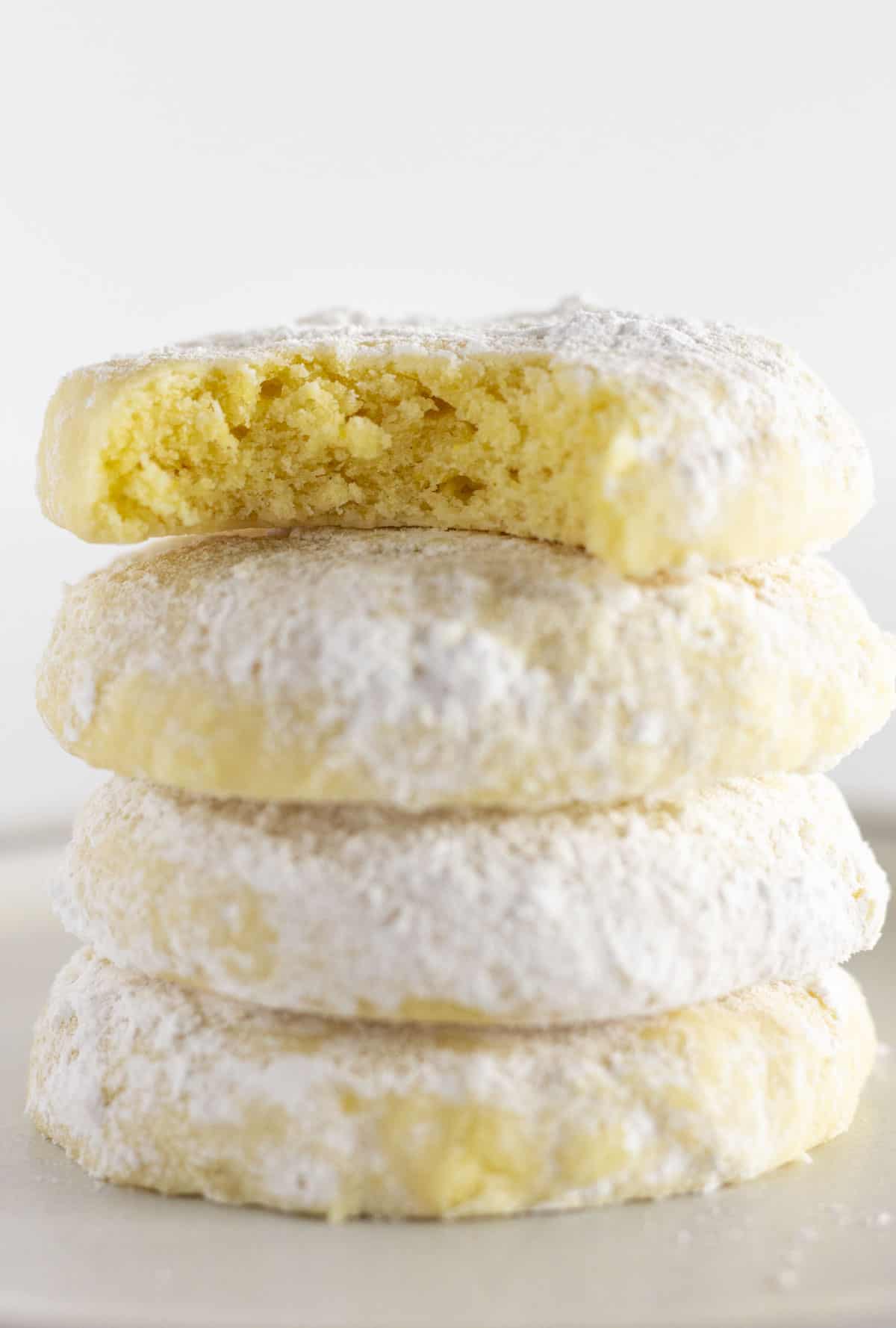 Four lemon cooler cookies stacked on top of each other with the top one having a bite taken out.