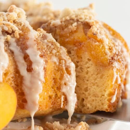 A peach cobbler cake with a slice being served.