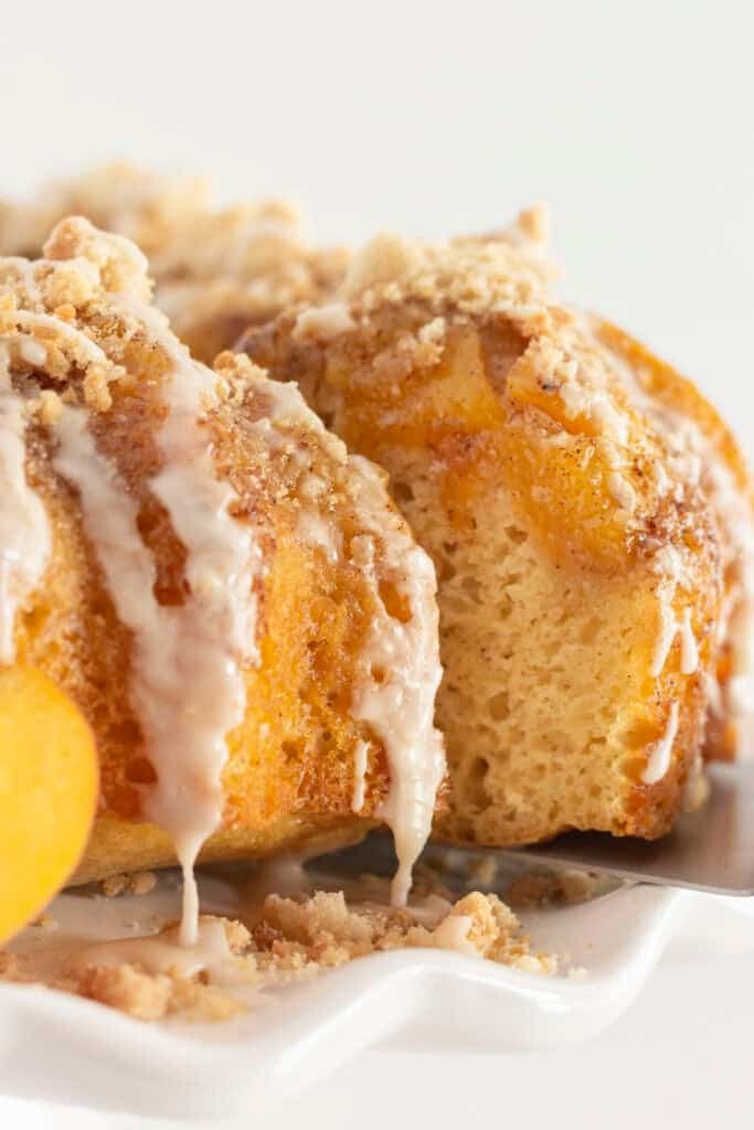 A peach cobbler cake with a slice being served.