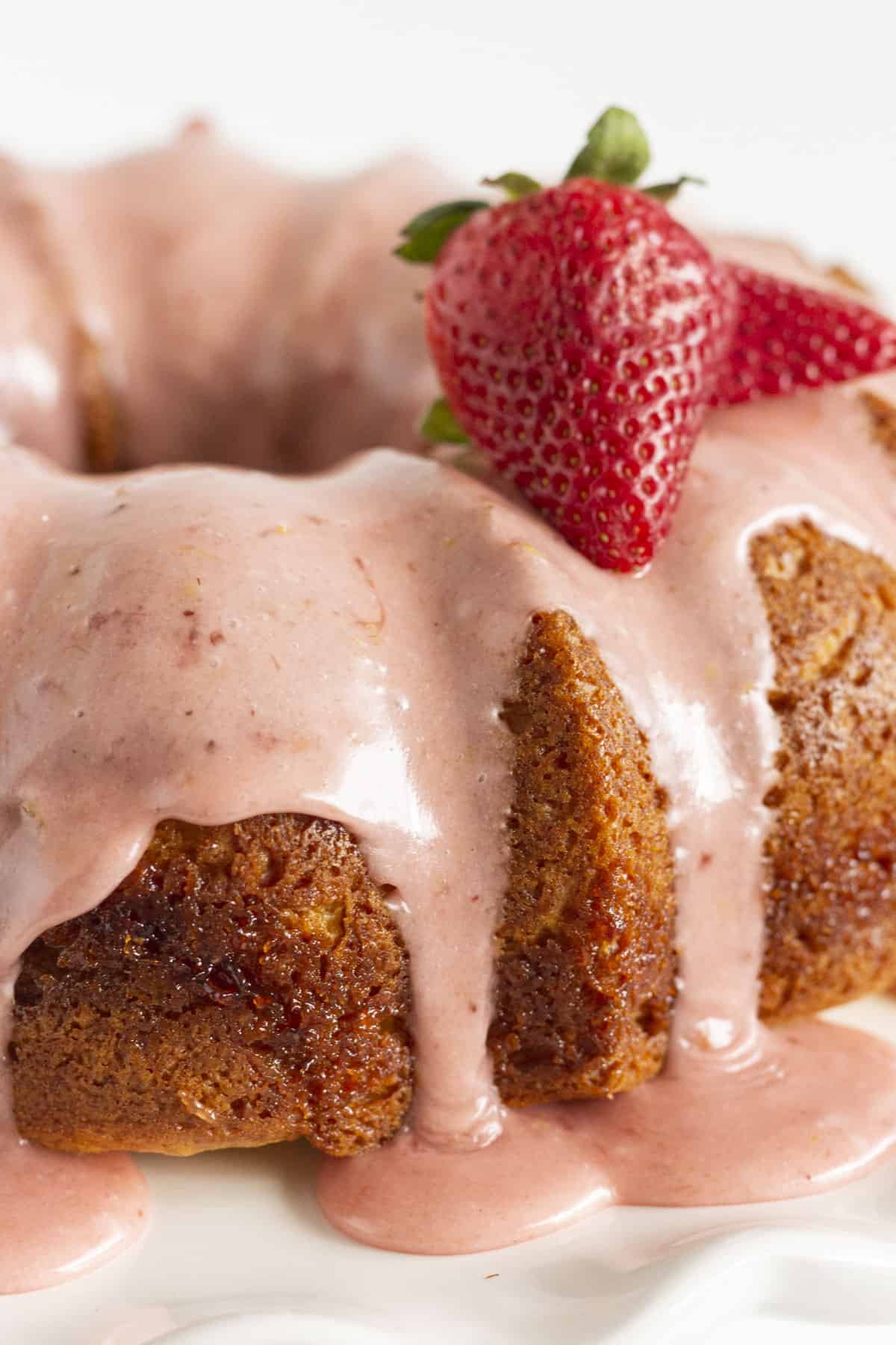 A finished strawberry lemonade bundt cake with a couple fresh strawberries on top.