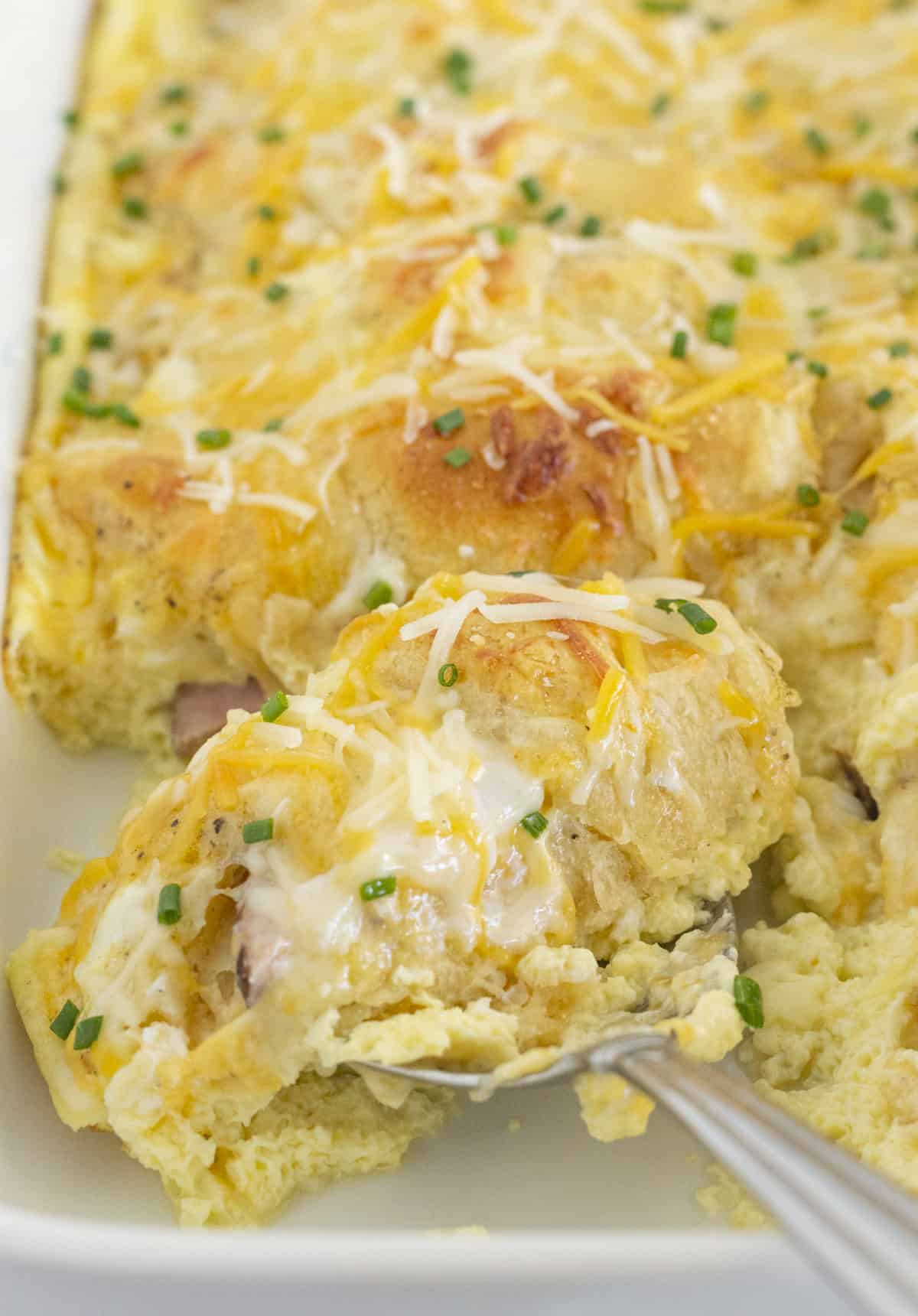 Serving easy cheesy ham and egg breakfast casserole.