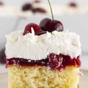 Serving a slice of white forest cake with a fresh cherry on top.