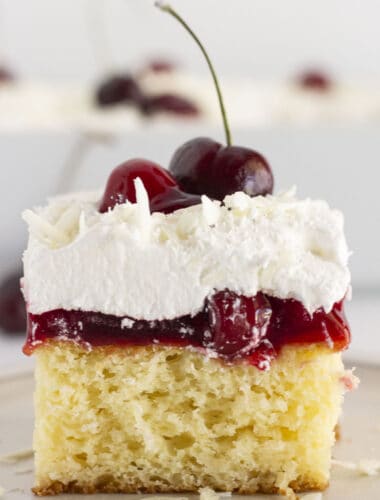 Serving a slice of white forest cake with a fresh cherry on top.