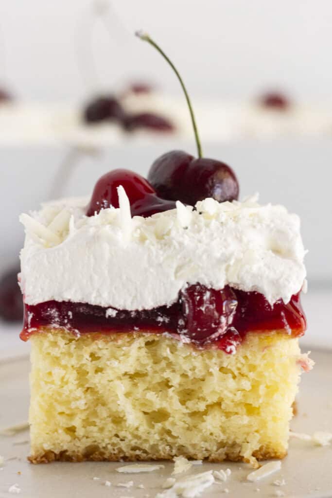 Serving a slice of white forest cake with a fresh cherry on top.