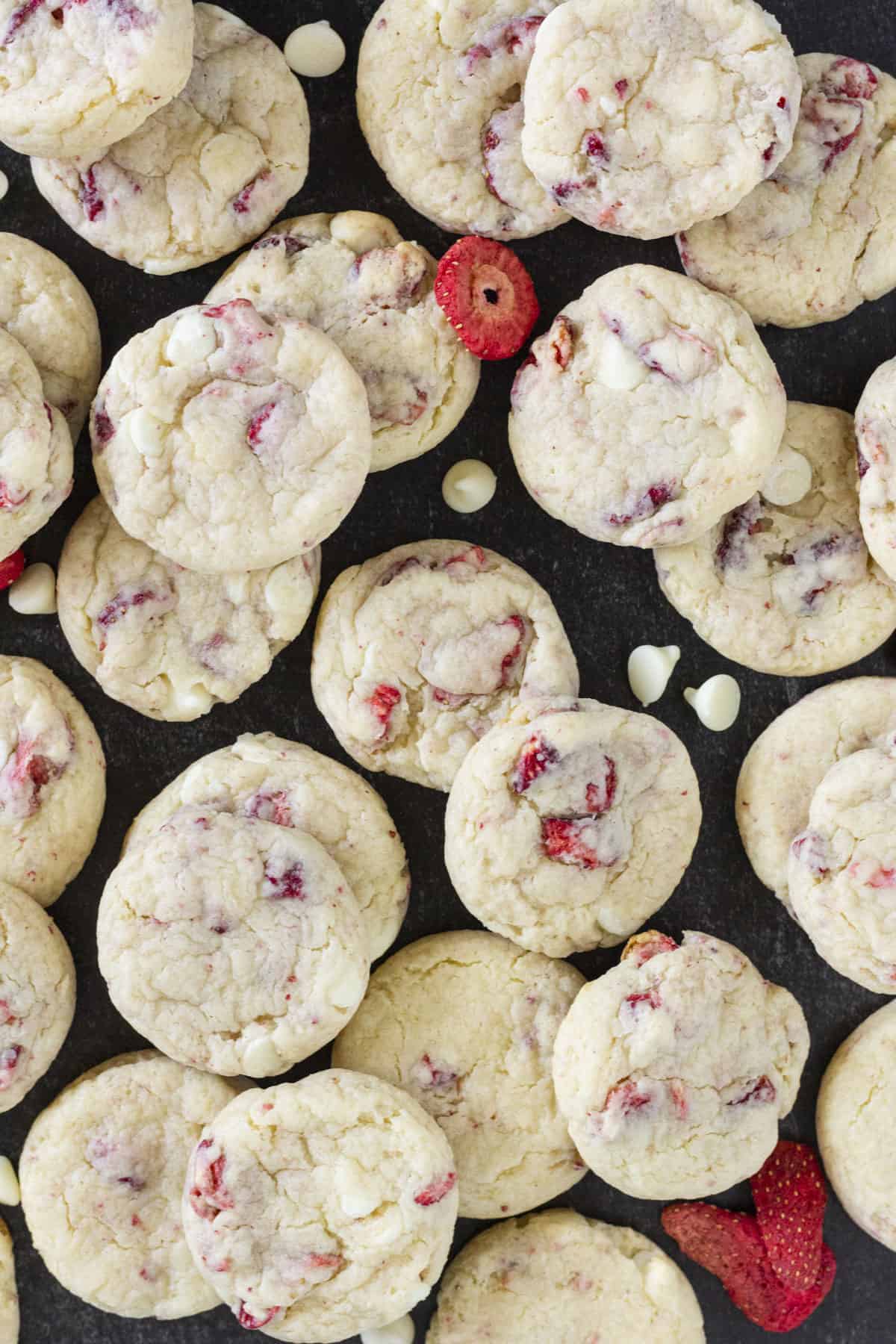 Dozens of strawberry cream cheese cookies on a black tray.