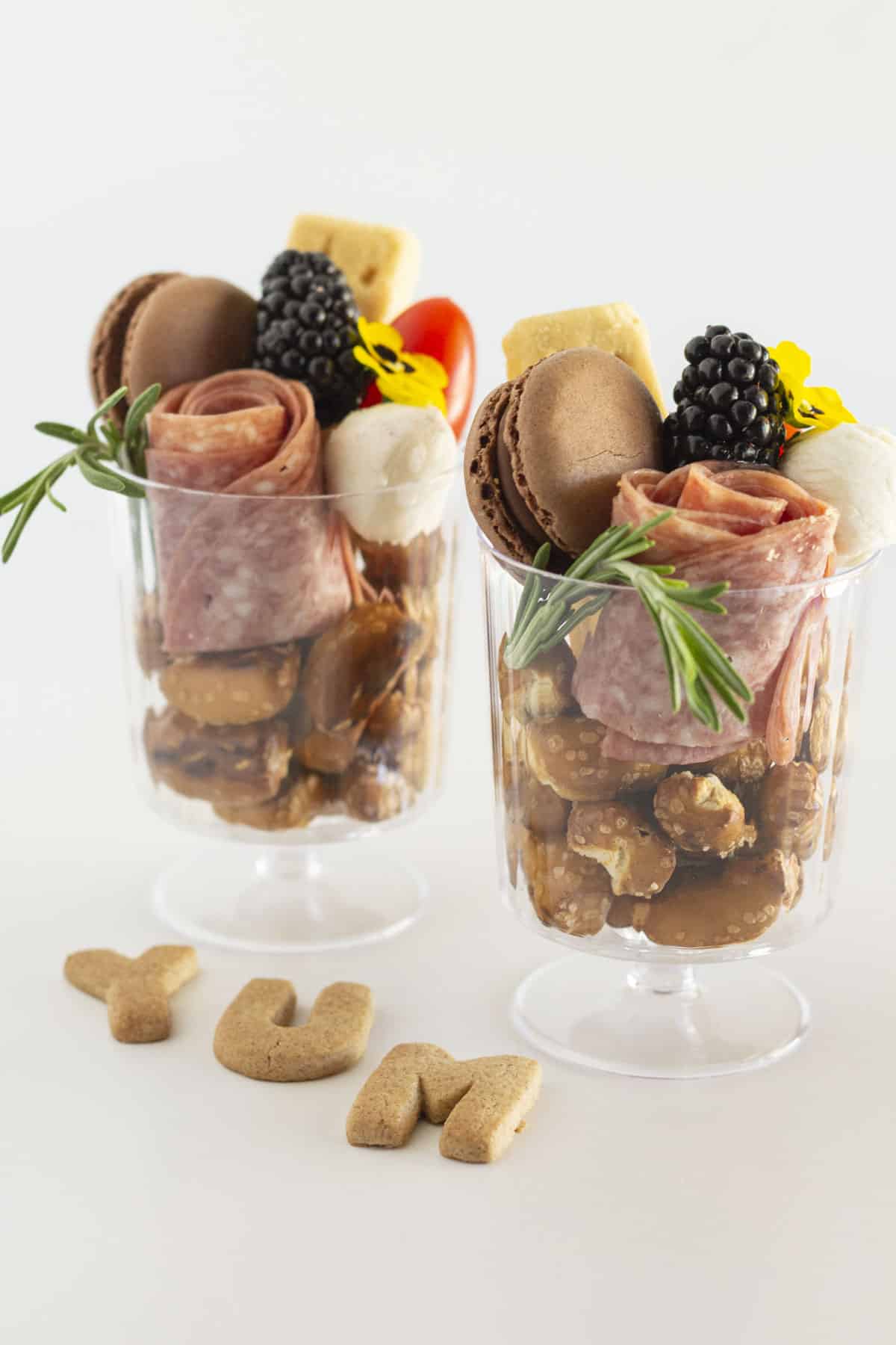 Two individual charcuterie cups in clear cups with salami roses.