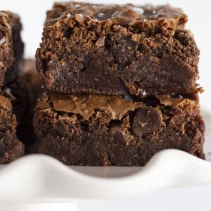 Condensed milk brownies stacked on a white plate.