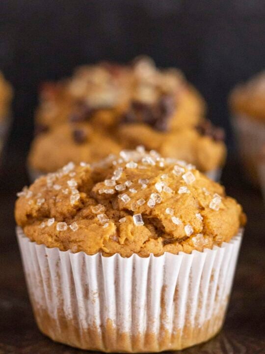 A dozen pumpkin muffins on a black tray.