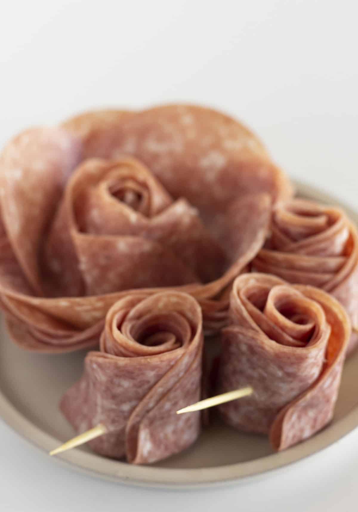 Salami roses on a white plate.