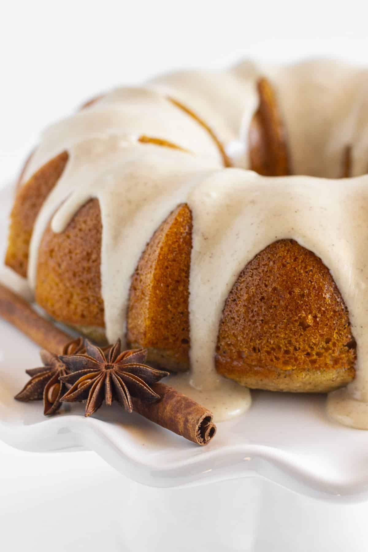 A frosted spice bundt cake on a white plate.