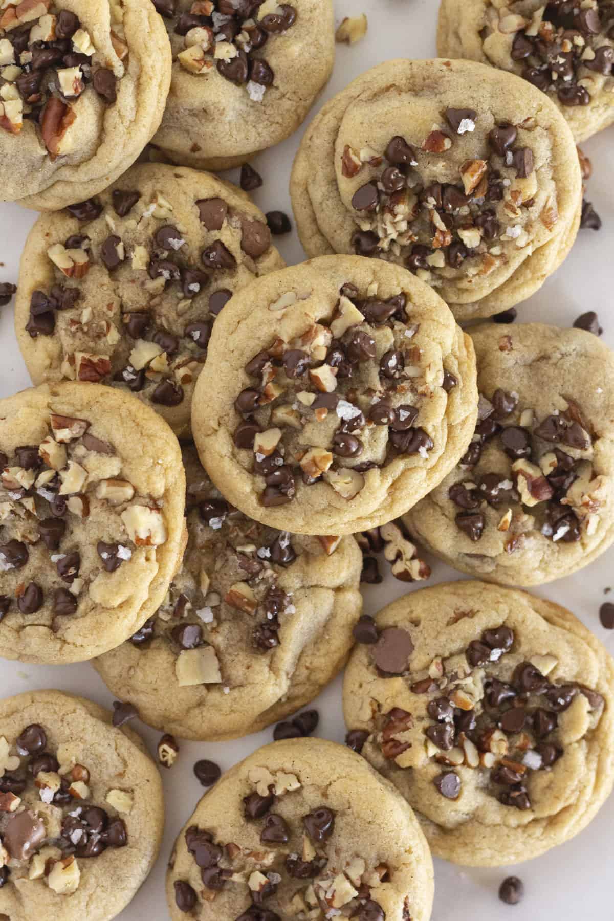 A dozen chocolate chip and pecan cookies on a white tray.