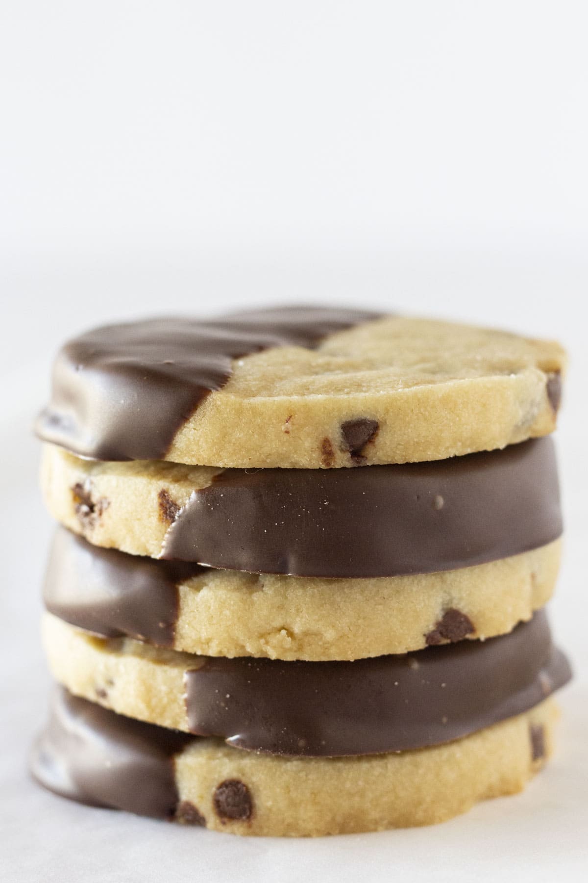 Chocolate dipped chocolate chip shortbread stacked on each other.