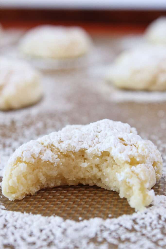 Cream cheese cookies on a baking sheet with powdered sugar.