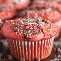 Red Velvet Muffins on a dark tray with powdered sugar and chocolate chips.