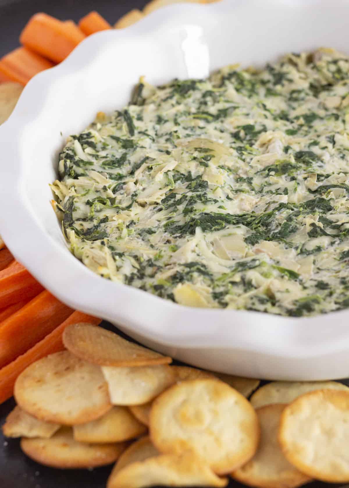 Spinach and artichoke dip served with crackers and carrots.