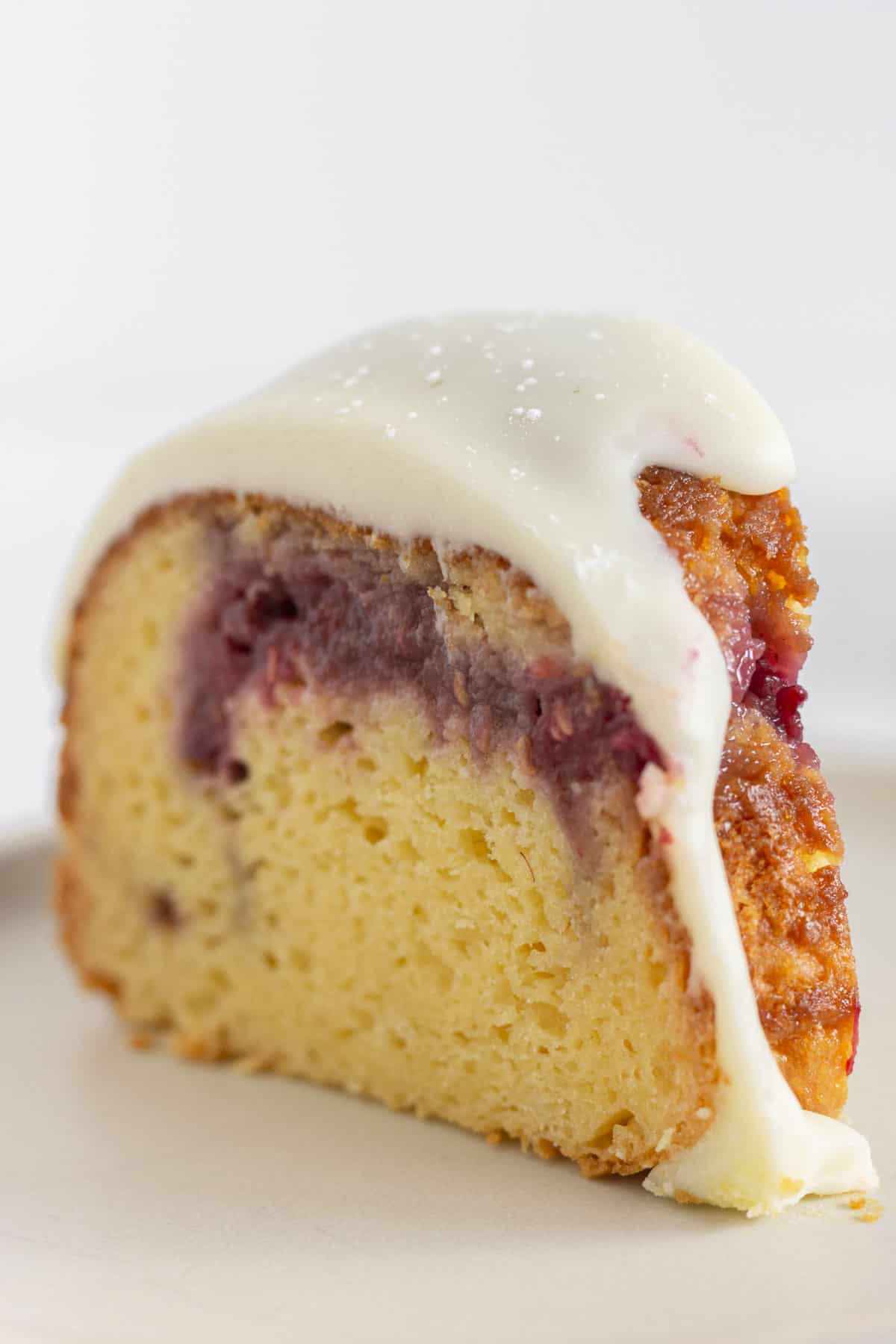 A slice of raspberry cake with white chocolate ganache.
