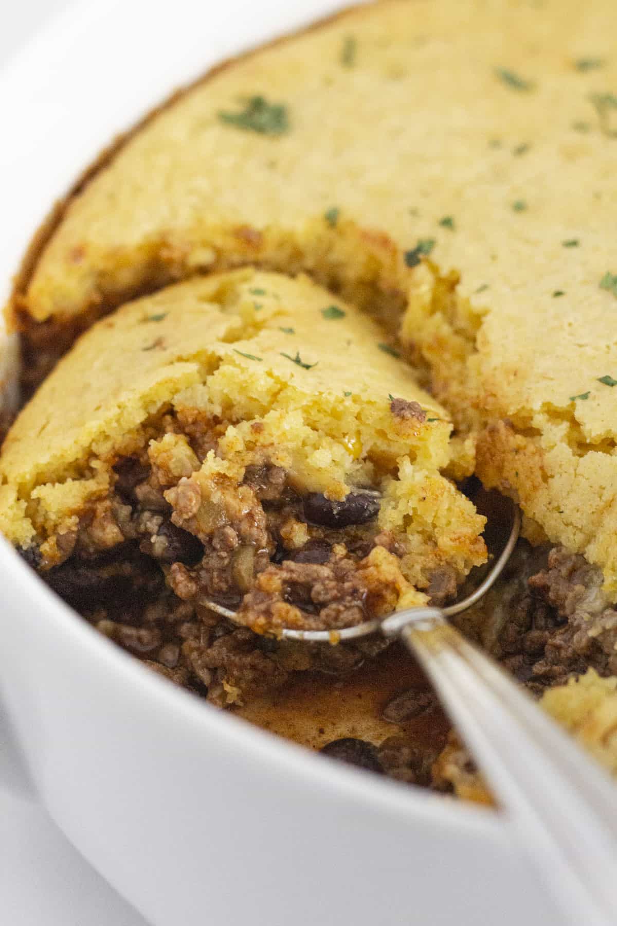 Scooping delicious Jiffy Tamale Pie with a spoon.
