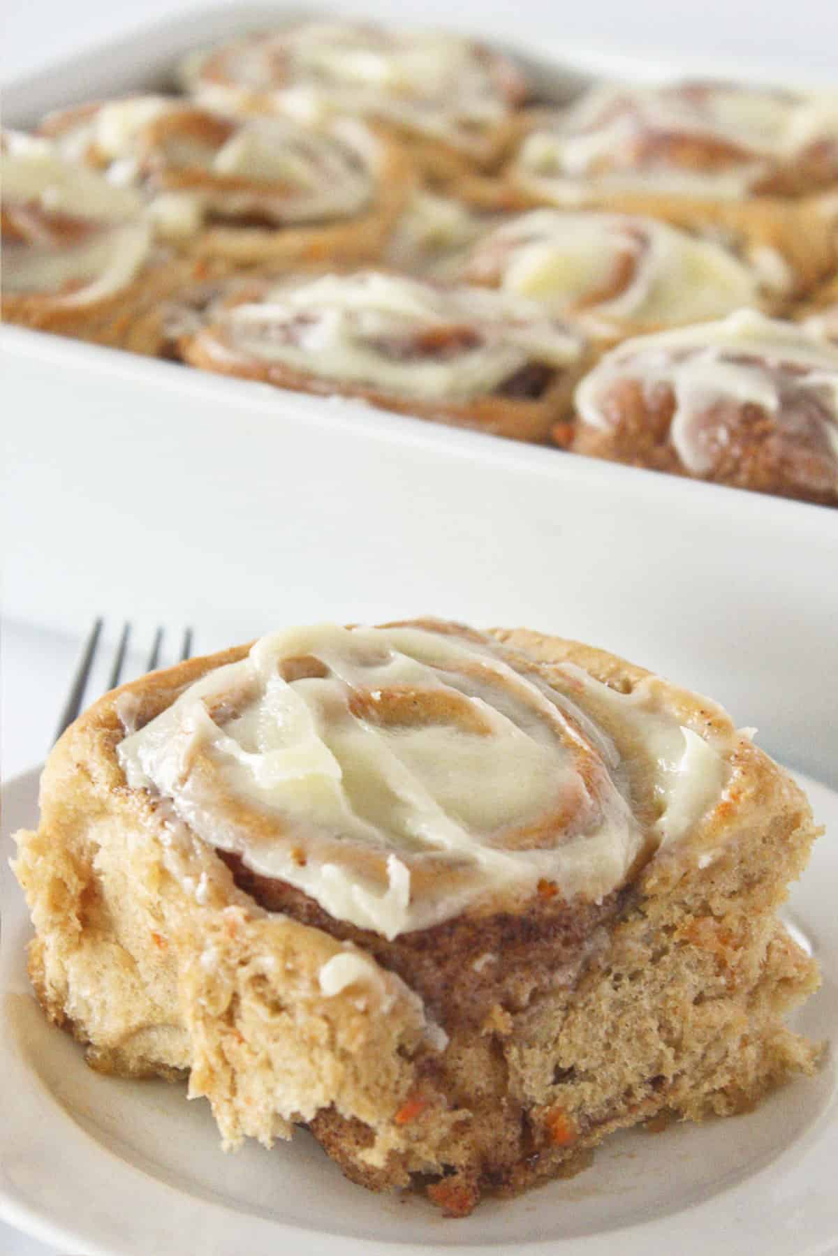 Serving one carrot cake cinnamon roll with cream cheese icing.