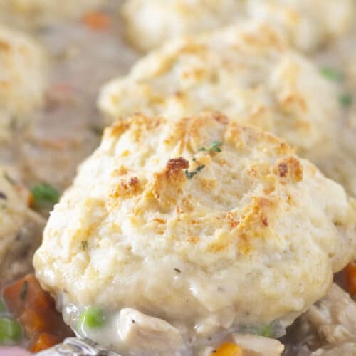 Serving chicken and biscuits casserole with a spoon.