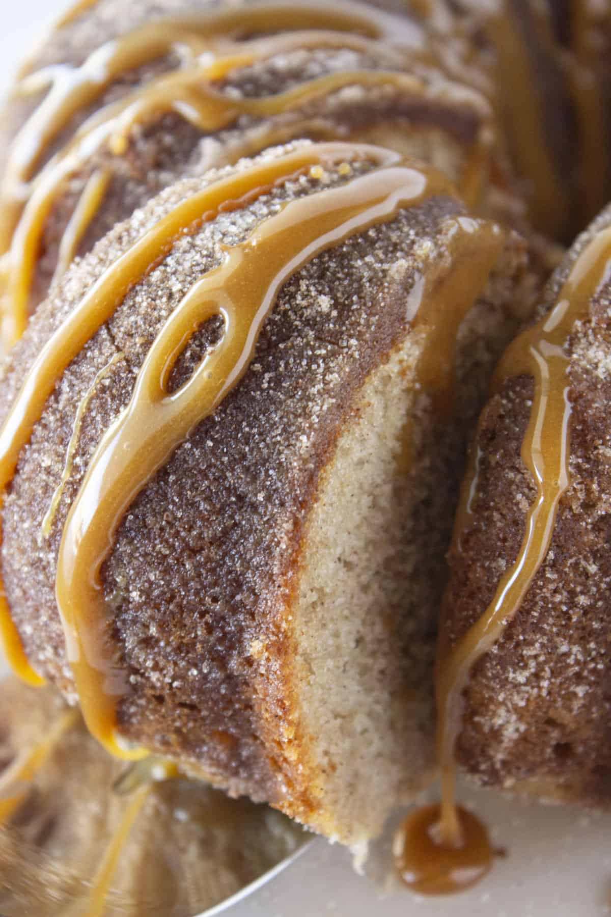 Serving a slice of churro bundt cake with caramel drizzled on top.