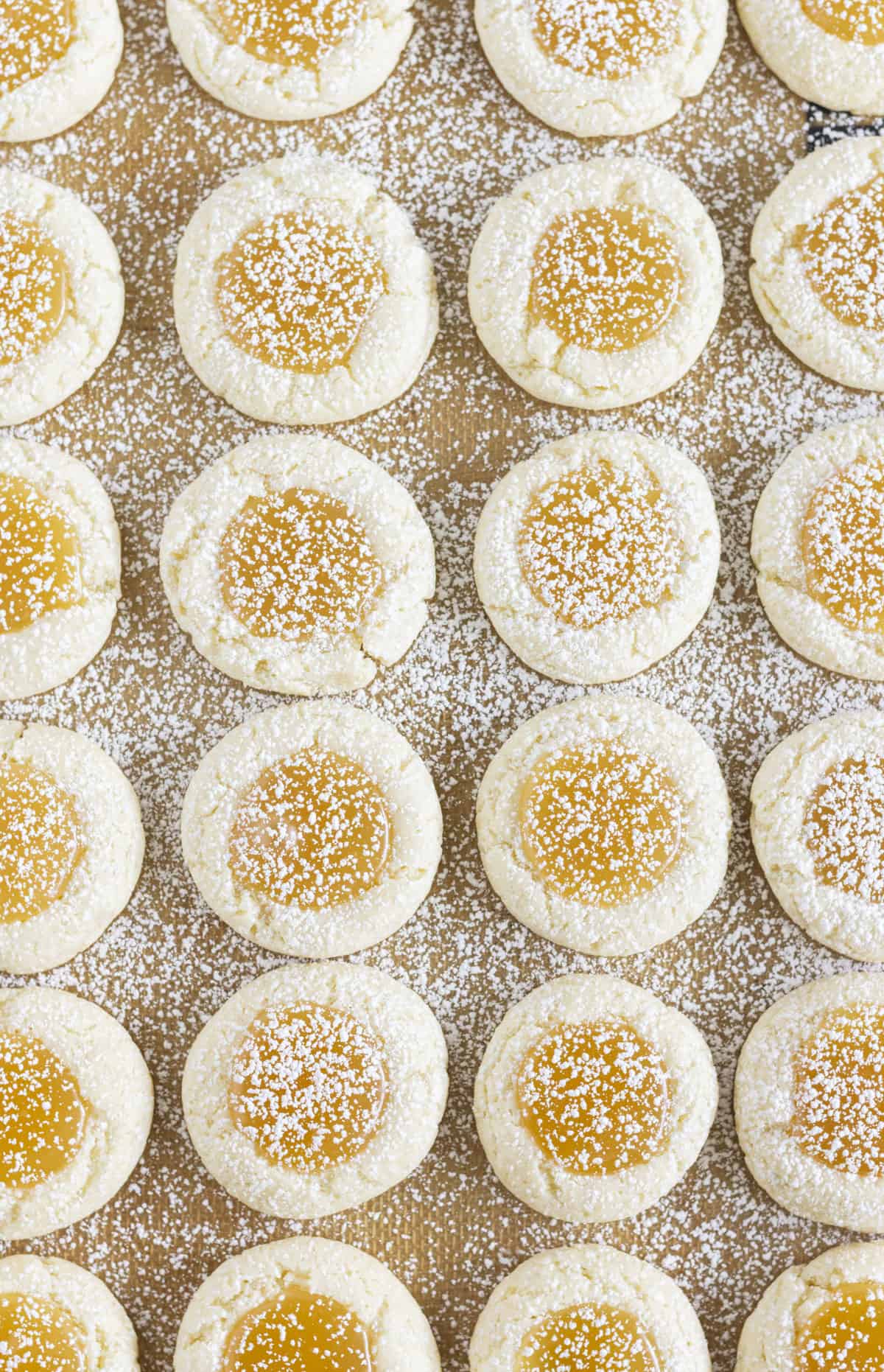 Lemon curd cookies on a sheet pan and sprinkled with powdered sugar.