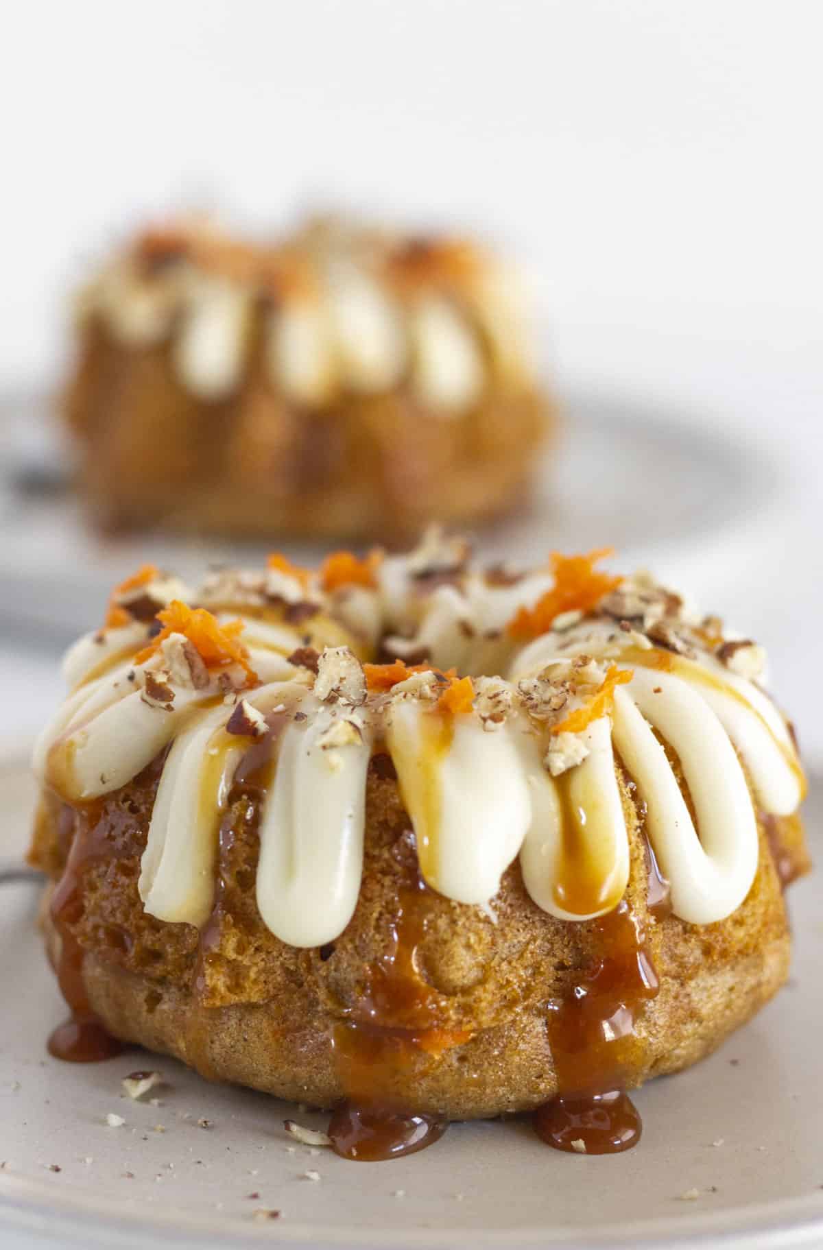 Two mini carrot bundt cakes on plates and ready to serve.