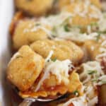 Serving chicken parm ravioli bake with a spoon.