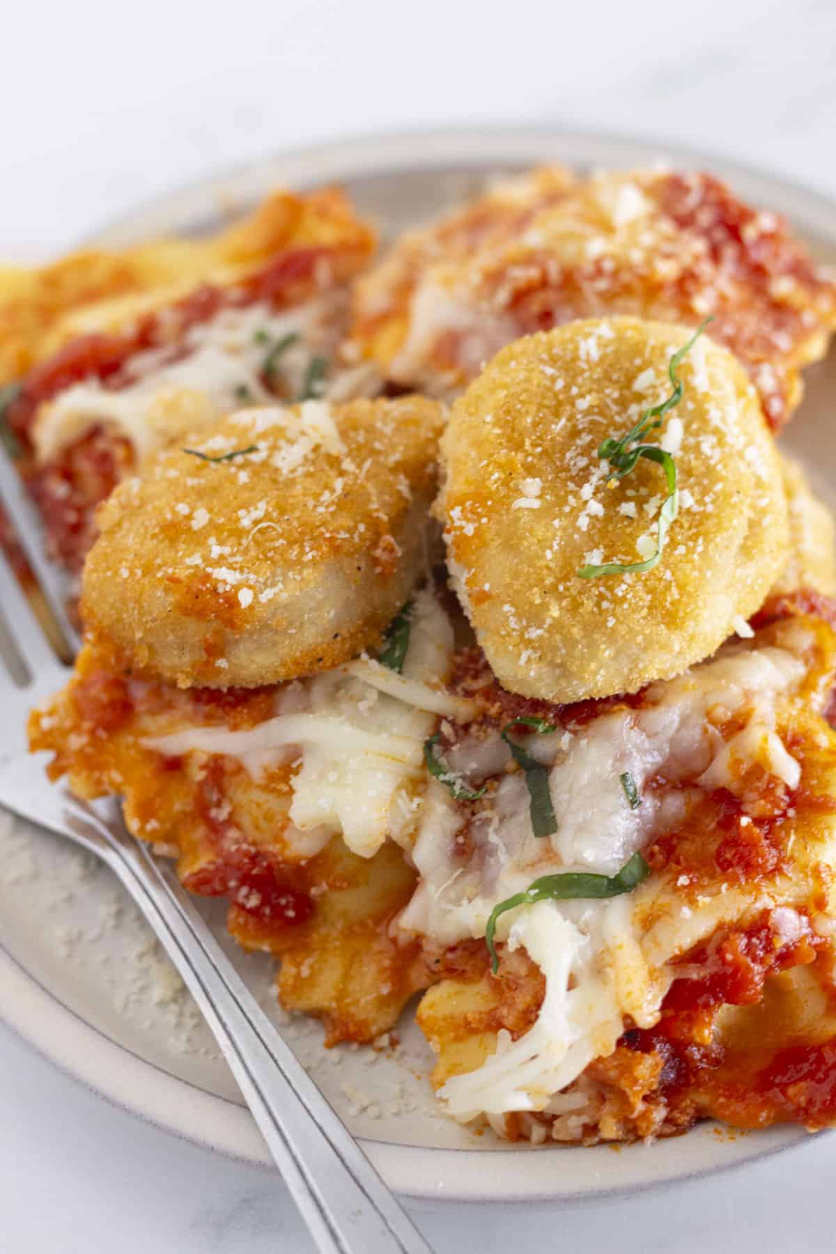 A serving of chicken parm ravioli bake on a white plate.