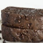 Two slices of chocolate zucchini loaf stacked on a white plate.