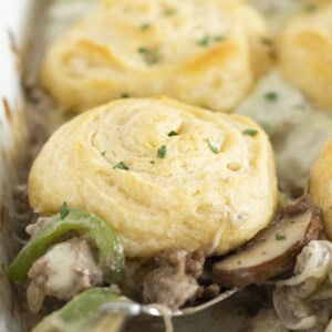 Serving a spoonful of Philly Cheesesteak casserole with crescent roll top.