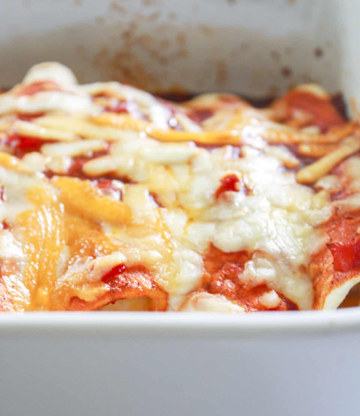 Baked shrimp enchiladas in a white baking pan with melted cheese.