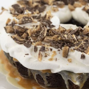 A finished Better Than Anything Cake with whipped topping and chopped candy bar.