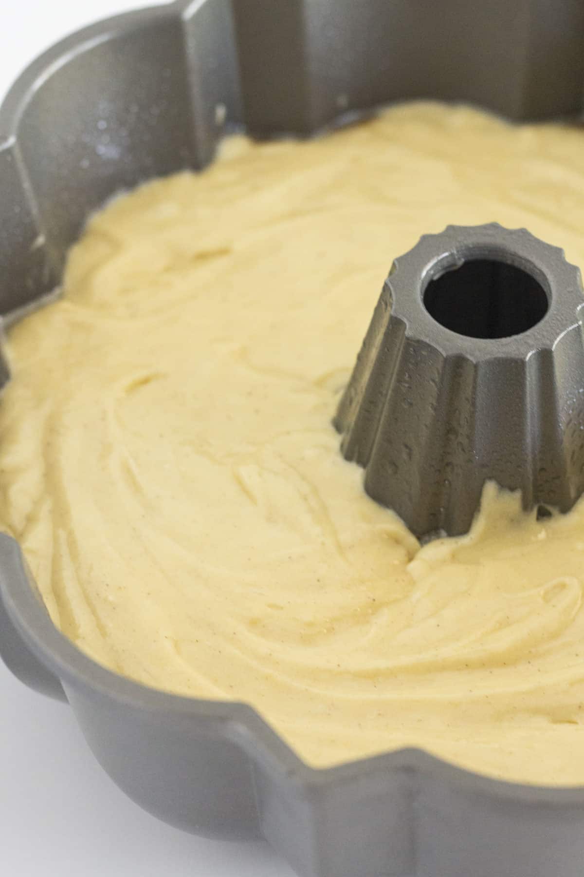 Pound cake batter in an even layer in a bundt pan.