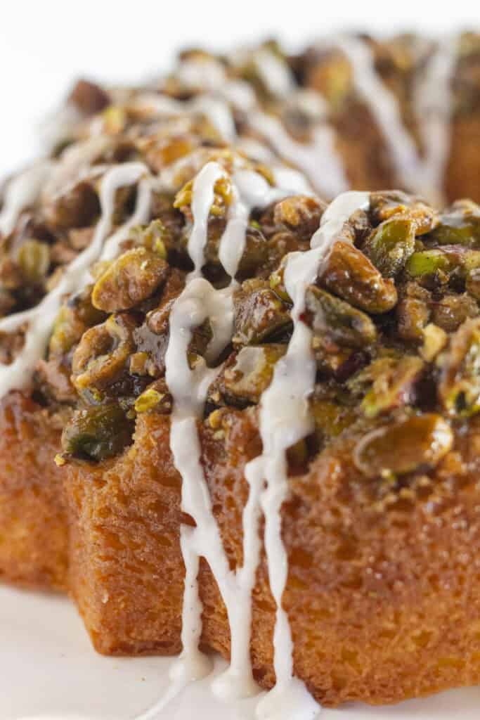 A close up of pistachio bundt cake with vanilla glaze.