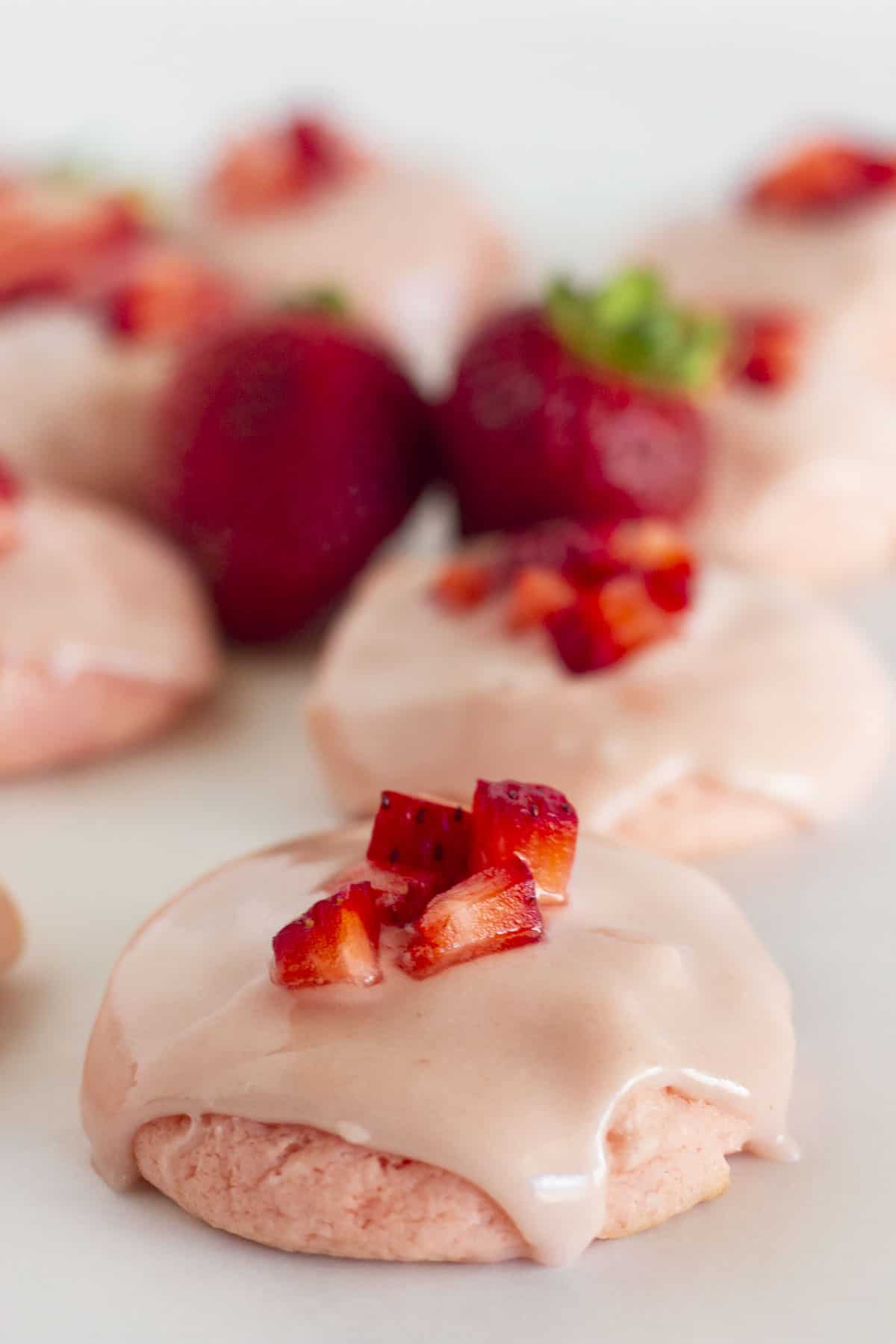 Strawberry Cake Mix Cookies on a white tray with fresh berries on top.
