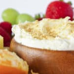 Cheesecake dip for fruit in a wood bowl and served with fresh fruit.