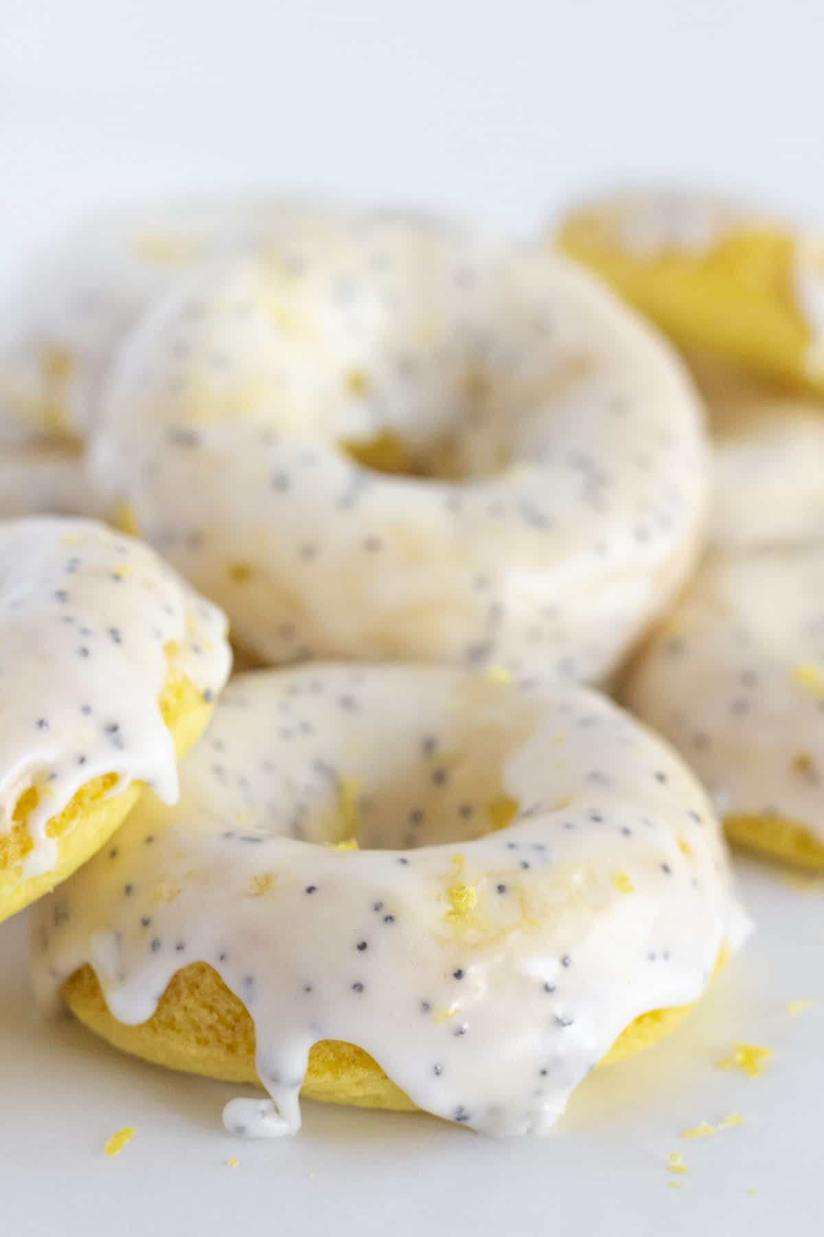 Lemon donuts with poppy seed glaze stacked on each other.