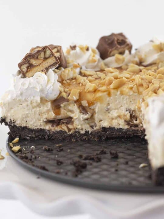 Looking inside a Snickers cheesecake that a has a few slices missing.