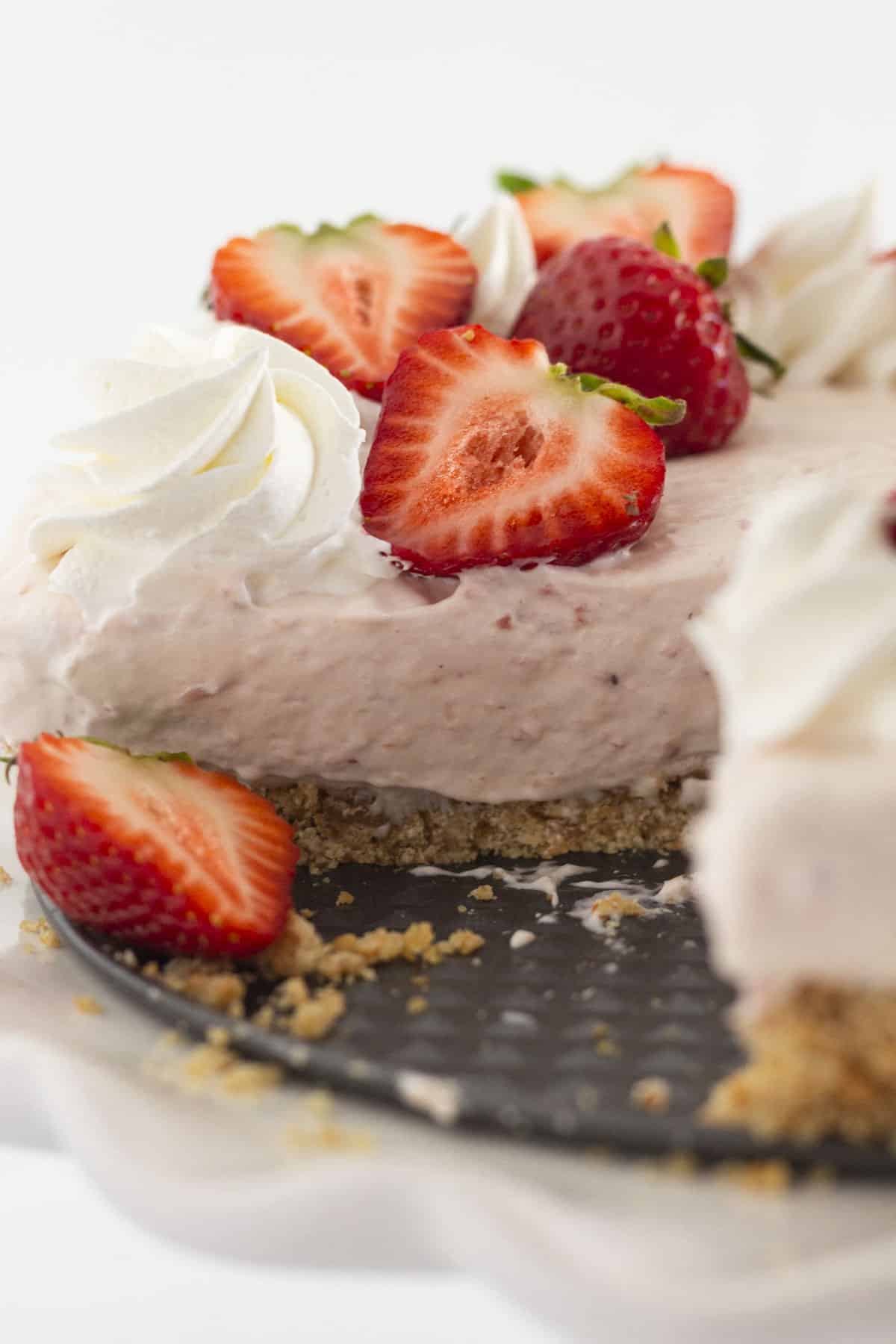 Looking at the inside of a strawberry no bake cheesecake with a few slices removed.