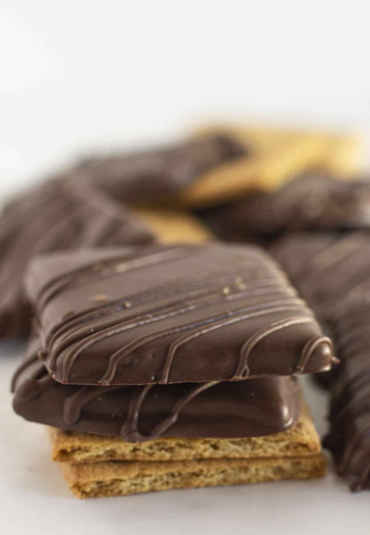 Stacked chocolate covered graham crackers on a plate.