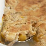 Serving a spoonful of warm peach cake mix cobbler.