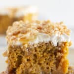 Two pieces of pumpkin poke cake on white plates.