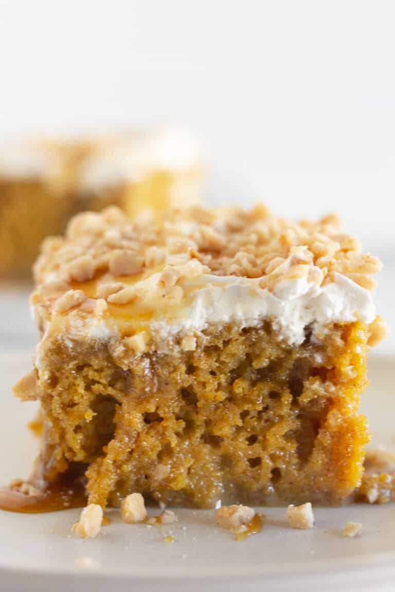 Two pieces of pumpkin poke cake on white plates.