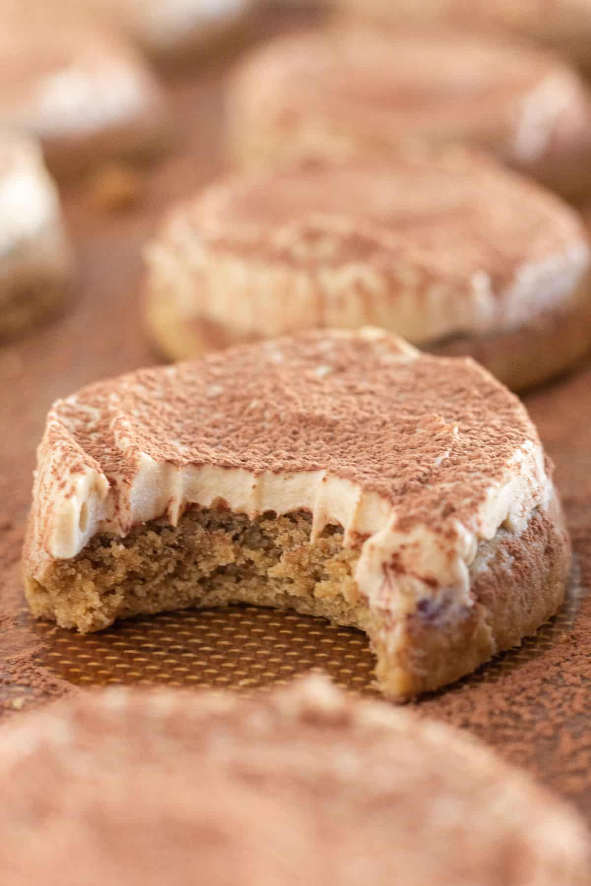 Tiramisu cookies on a cookie sheet with a bite taken out of one.