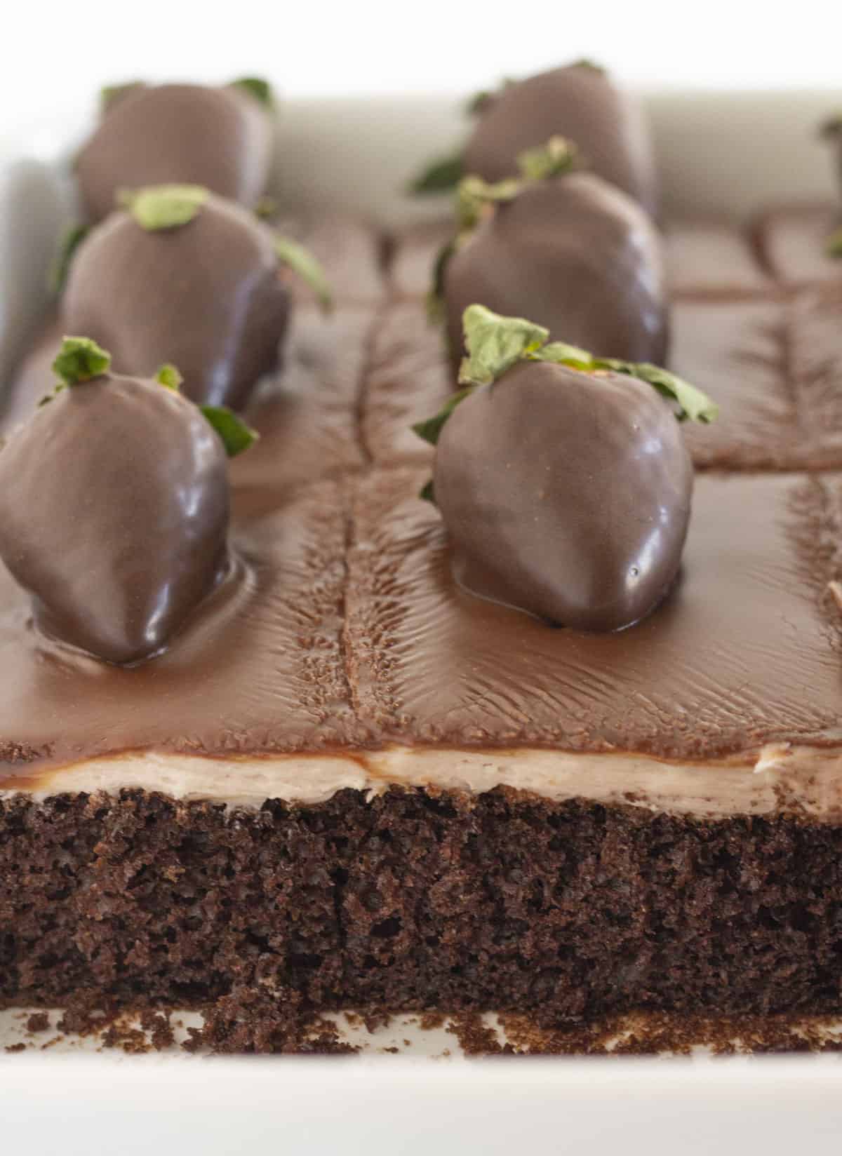 Un gâteau aux fraises enrobées de chocolat dont quelques morceaux ont déjà été mangés.